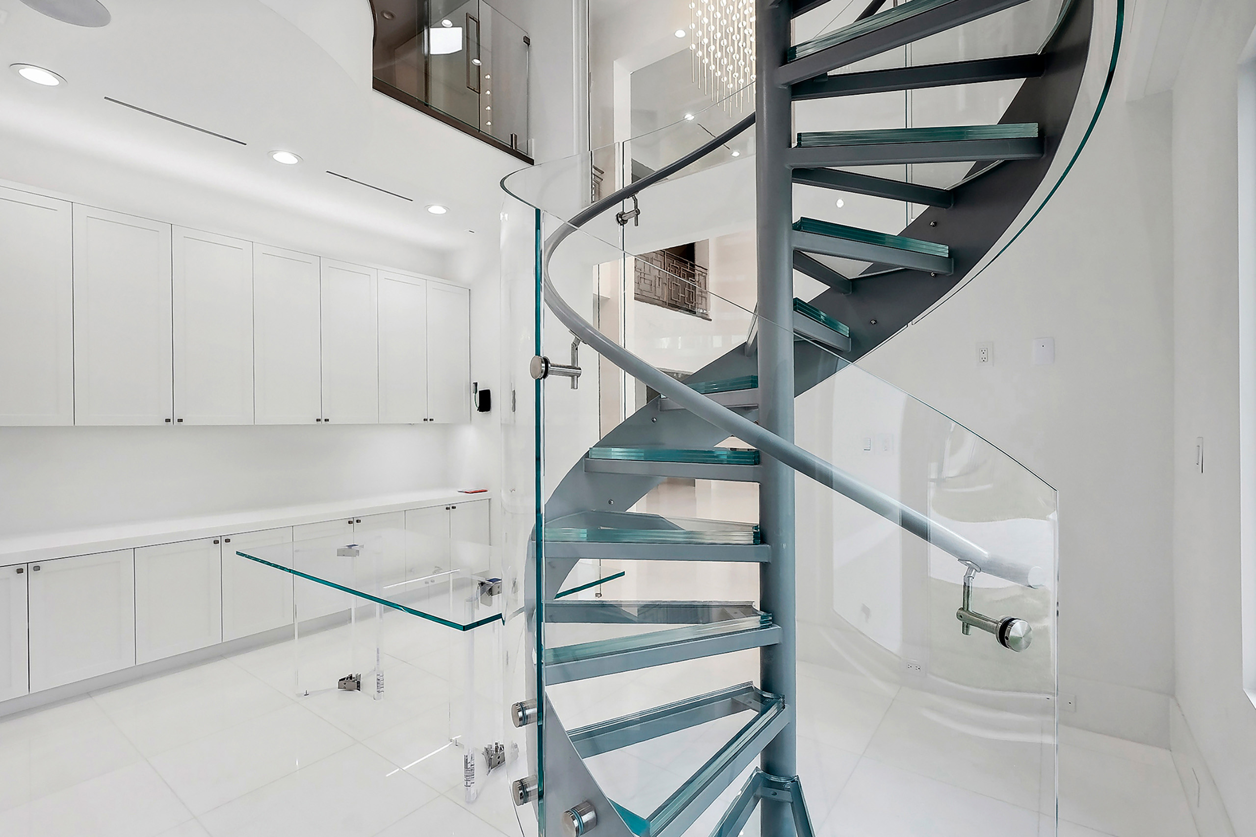 Elegantly designed circular staircase with glass railing and treads ...